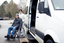 Nurse helping senior man exit a van