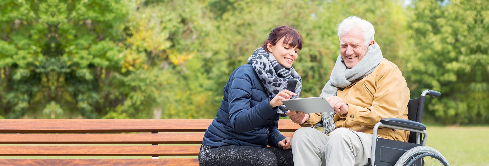 caregiver and elder man looking at the tablet