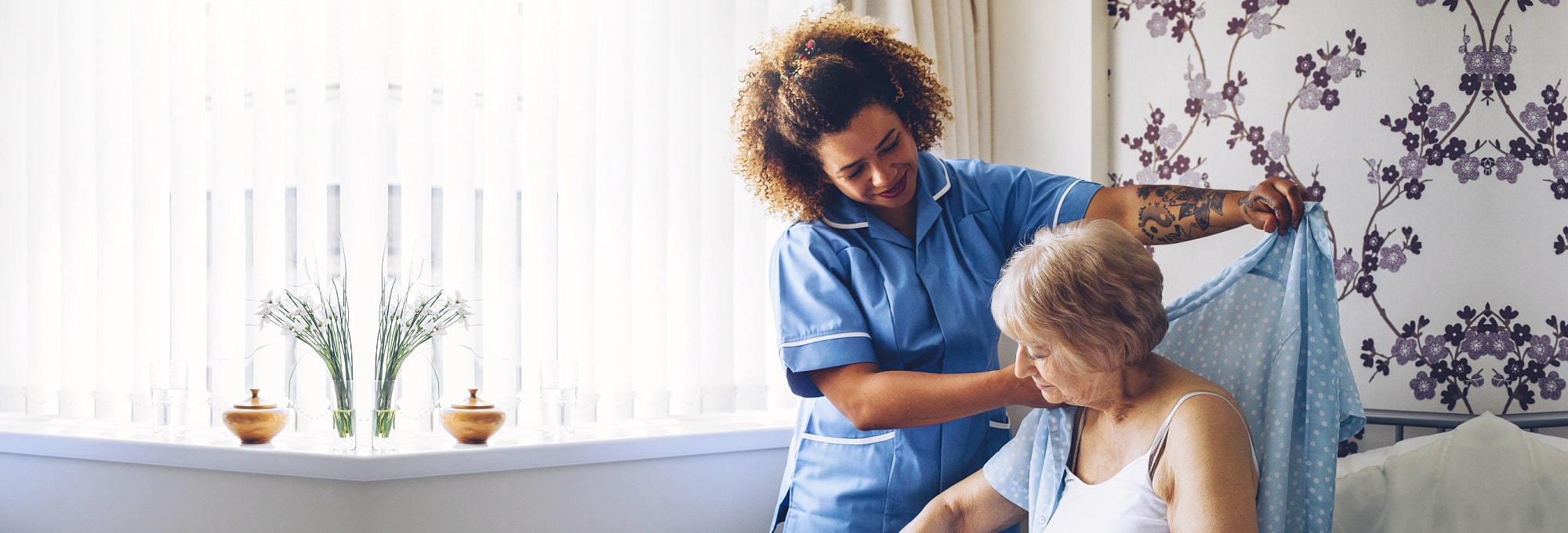 caregiver assisting elder woman get dressed