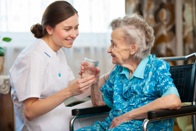 caregiver serving a glass of water for elder woman