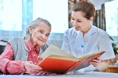 elder woman and caregiver looking together at album